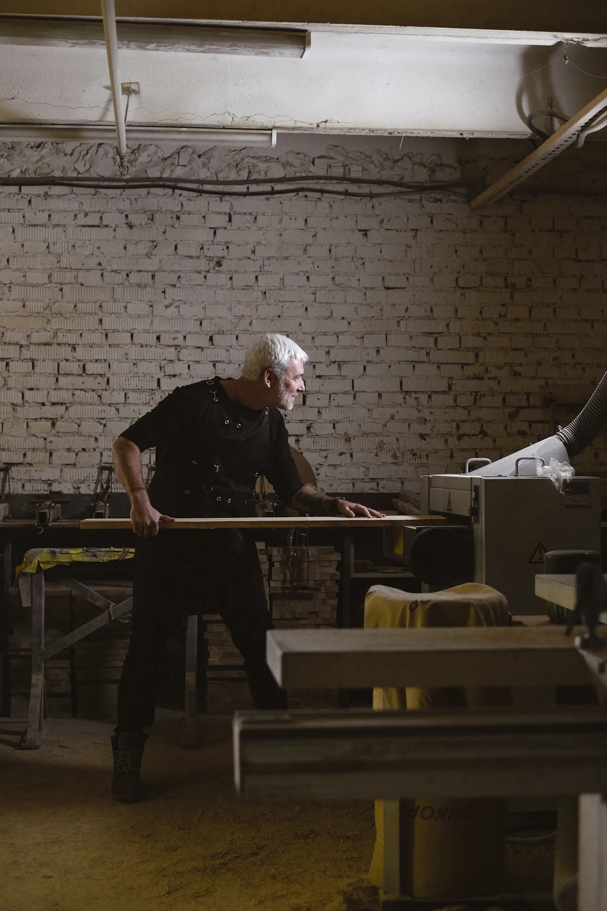 Menuisier passant une pièce de bois à la machine dans son atelier