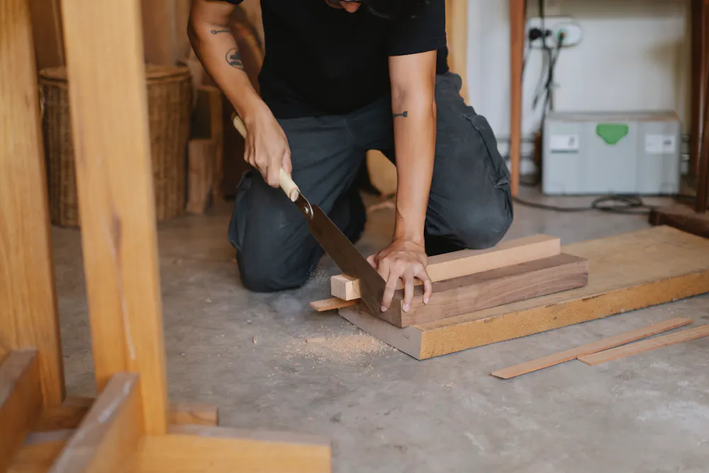 Mains d'un menuisier découpant une pièce de bois dans l'atelier