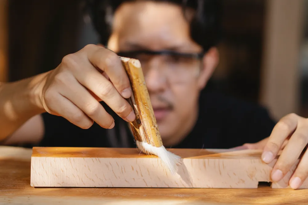 Artisan appliquant une finition sur une pièce de bois